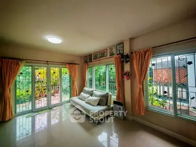 Spacious living room with large windows and garden view, perfect for relaxation.