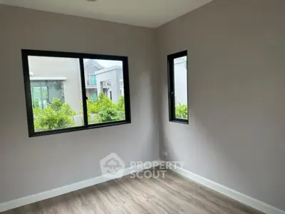 Spacious empty room with large windows and wooden flooring, ideal for customization.
