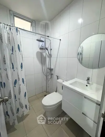 Modern bathroom with sleek white tiles and compact fixtures, featuring a shower and vanity unit.