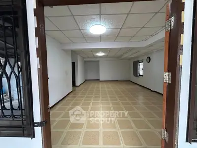 Spacious empty room with tiled flooring and ceiling lights, ideal for customization.