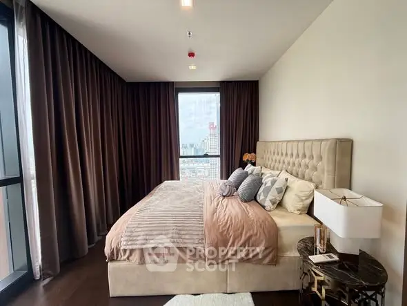 Luxurious bedroom with plush bedding and city view in modern apartment.