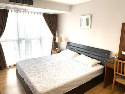 Bright and cozy bedroom with large window and modern furnishings.