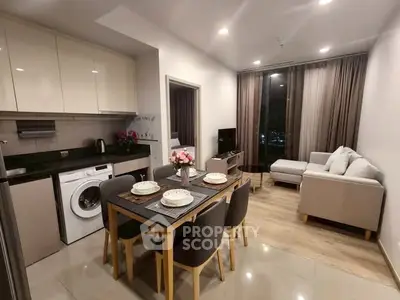Modern open-plan living room and kitchen with dining area, featuring sleek furniture and appliances.