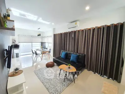 Modern living room with sleek furniture and open dining area, featuring large windows and stylish decor.