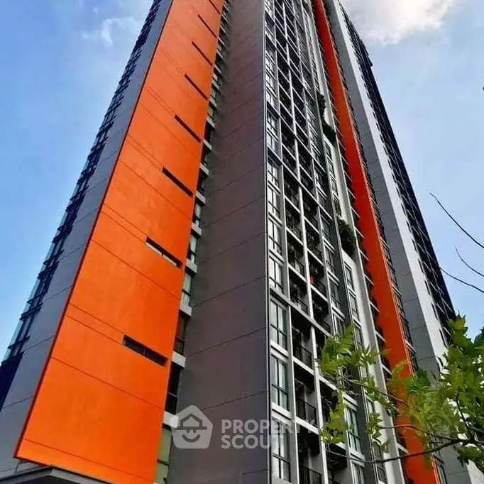 Modern high-rise building with vibrant orange accents and sleek design.