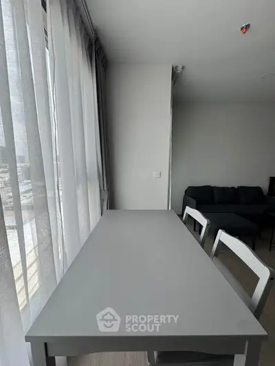 Modern apartment interior with sleek dining area and cozy living room, featuring large windows for natural light.