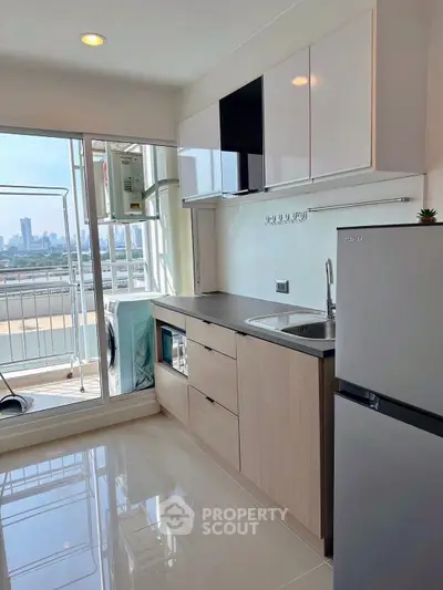 Modern kitchen with city view, sleek cabinetry, and balcony access in urban apartment.