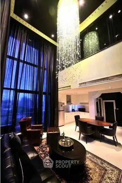 Luxurious high-ceiling living room with elegant chandelier and modern open kitchen