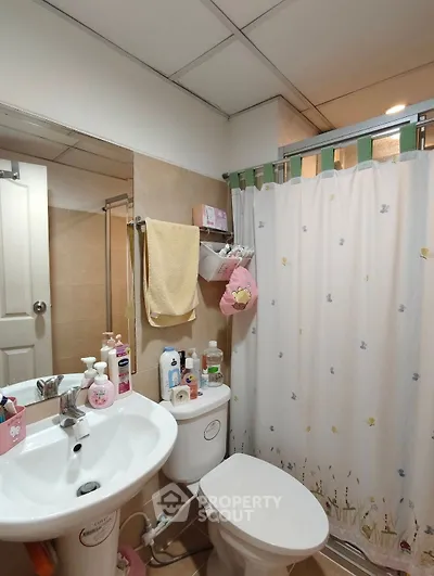 Cozy bathroom with modern fixtures and charming decor, featuring a shower curtain and ample storage space.
