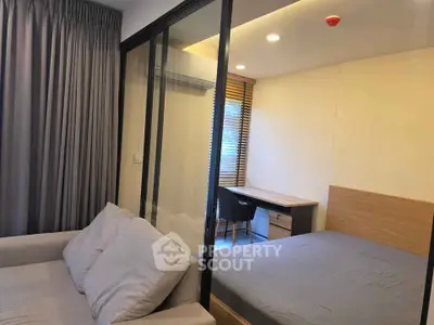 Modern studio apartment with glass partition, cozy bed, and study area.