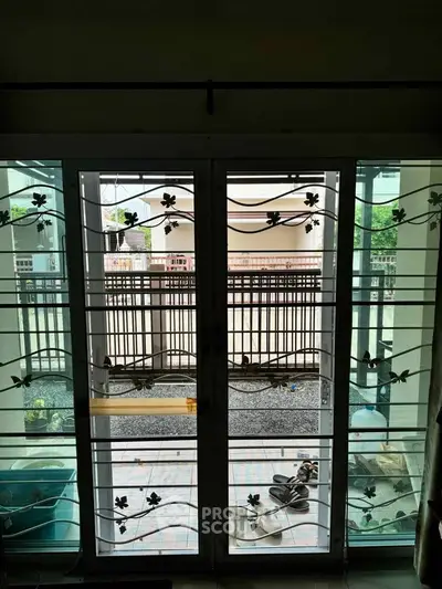 Spacious balcony view with decorative metal doors and outdoor area