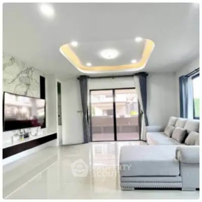Spacious modern living room with elegant ceiling design and large windows.