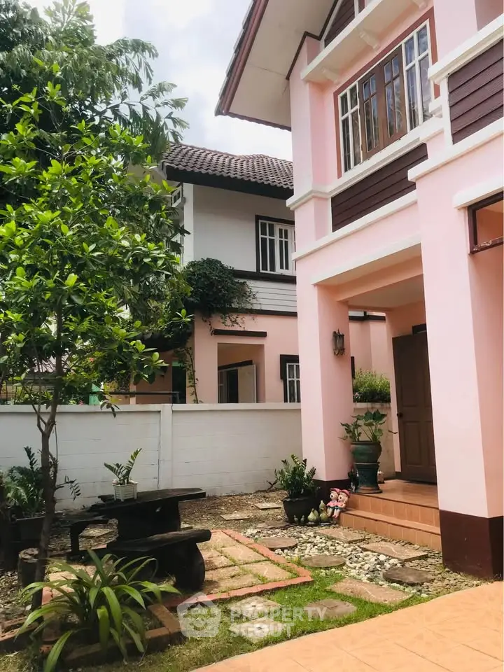 Charming pink house with lush garden and inviting entrance in a serene neighborhood.
