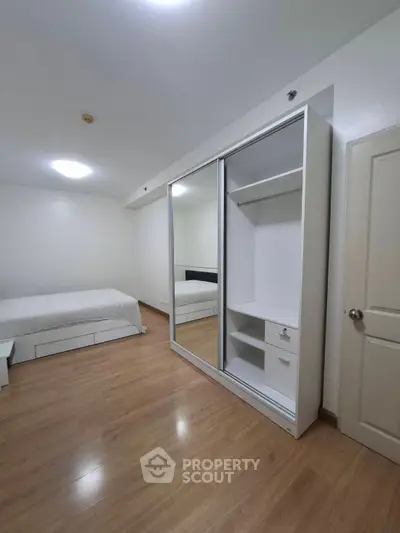 Spacious bedroom with wooden flooring and large mirrored wardrobe
