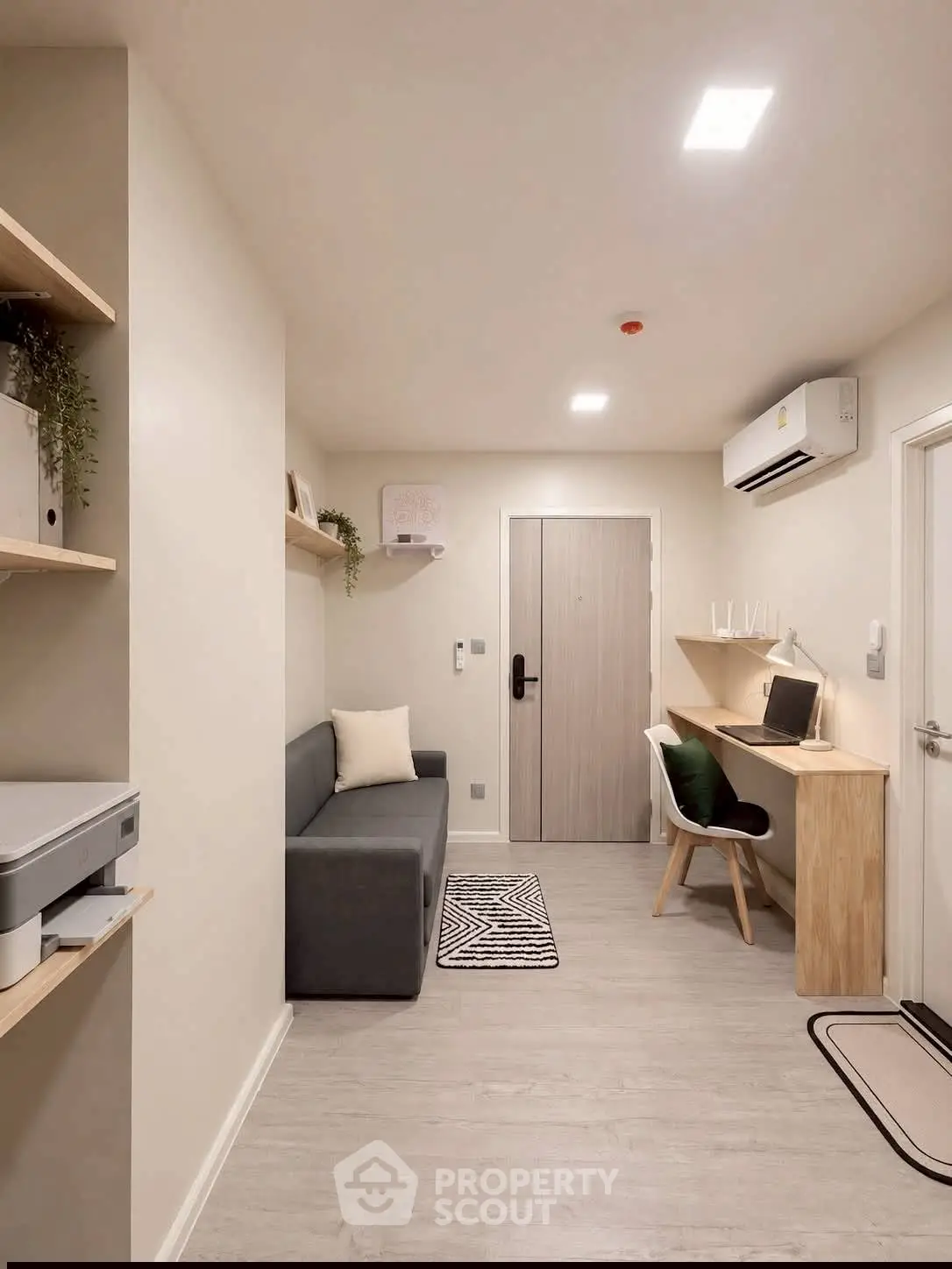 Modern living room with sleek furniture and workspace, featuring air conditioning and stylish decor.