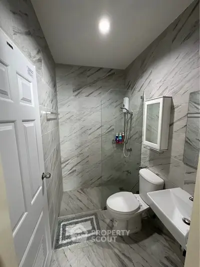Modern bathroom with sleek marble tiles and glass shower enclosure