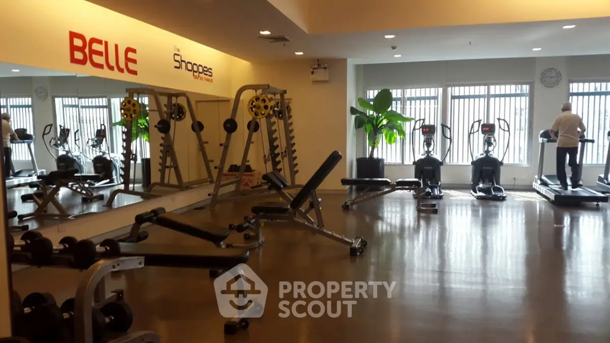 Spacious modern gym with exercise equipment and large mirrors in a residential building.