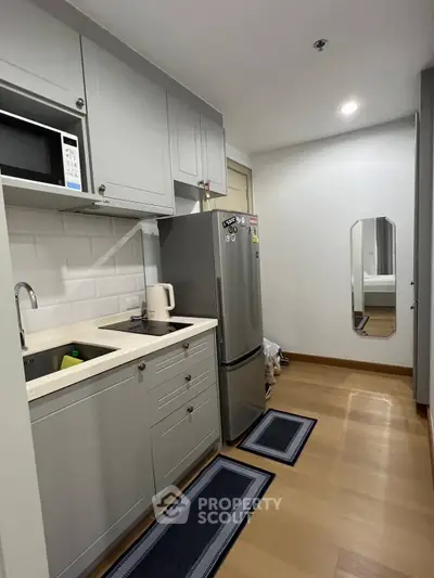 Modern compact kitchen with sleek cabinetry and stainless steel appliances in a cozy apartment.