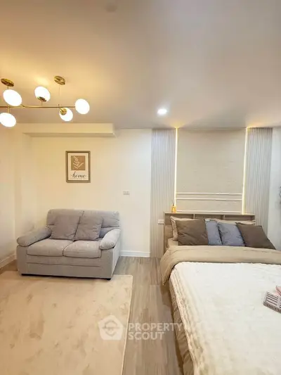 Modern bedroom with cozy bed and stylish sofa in a well-lit interior space.