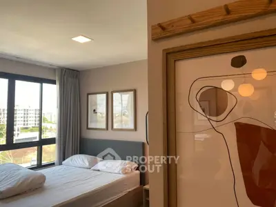 Modern bedroom with large window and abstract art, offering a bright and cozy atmosphere.