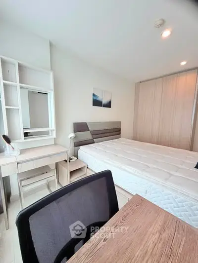 Modern bedroom with stylish furniture and ample natural light, featuring a comfortable bed and functional workspace.