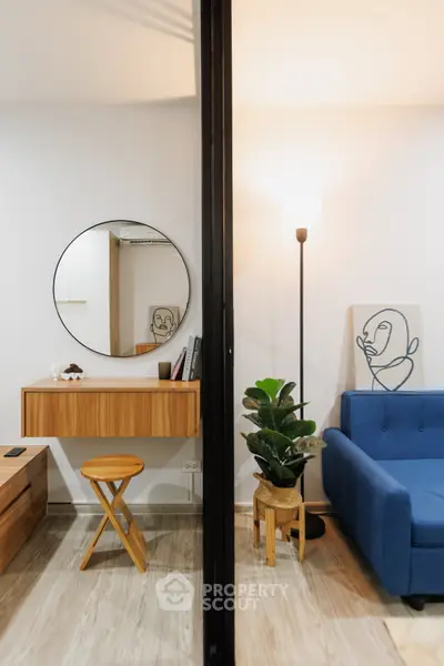 Modern living room with stylish decor, featuring a blue sofa, round mirror, and indoor plant for a cozy ambiance.