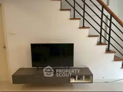 Modern living room with sleek TV unit under stylish staircase