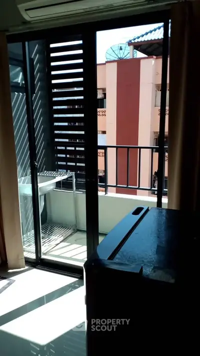 Modern apartment balcony with sliding glass doors and city view, perfect for urban living.