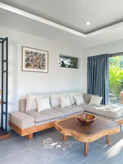 Modern living room with stylish wooden furniture and large windows overlooking lush greenery.