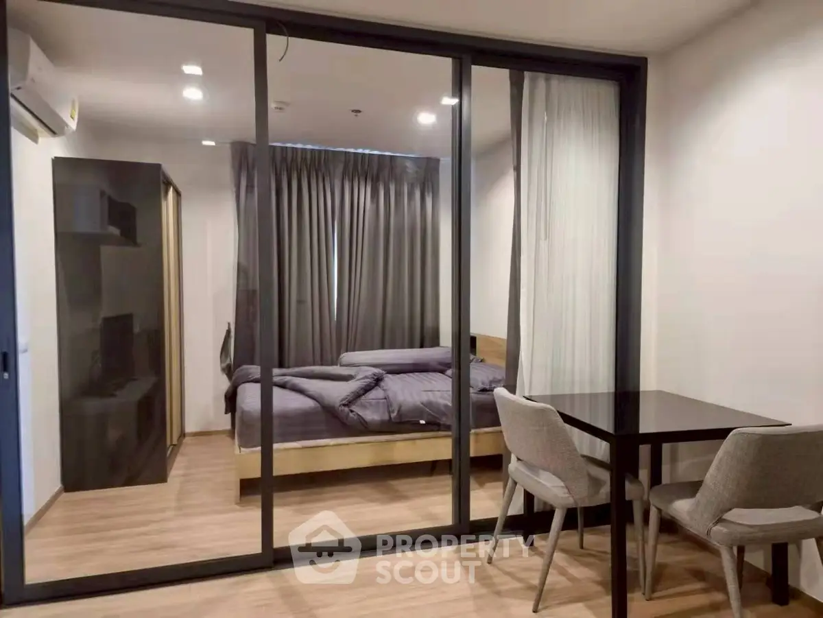 Modern bedroom with glass partition and cozy dining area in stylish apartment.