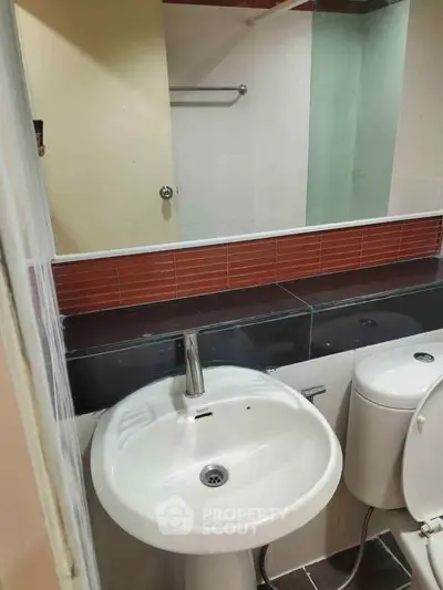 Compact bathroom with modern sink and toilet, featuring sleek design and neutral tones.