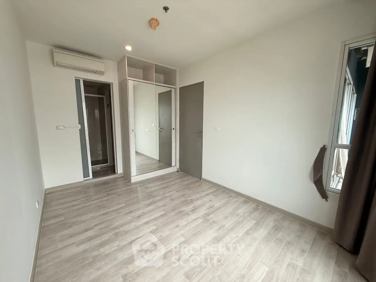 Spacious empty bedroom with mirrored wardrobe and large window