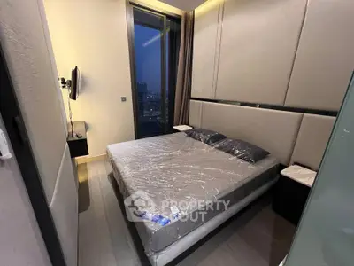 Modern bedroom with large window and sleek design in high-rise apartment.