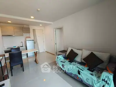 Modern open-layout living room with kitchen, featuring sleek furniture and bright lighting.