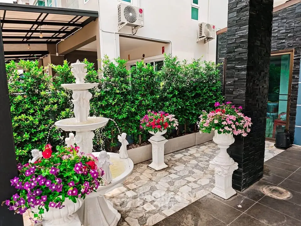 Charming garden with elegant fountain and vibrant flowers in modern real estate setting.