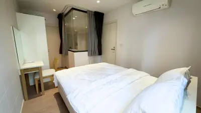 Modern bedroom with cozy white bedding and air conditioning in a stylish apartment.