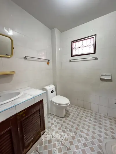 Spacious bathroom with modern fixtures and natural light, featuring a tiled floor and a large mirror.