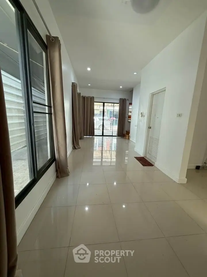 Spacious modern living room with large windows and glossy tiled floors.