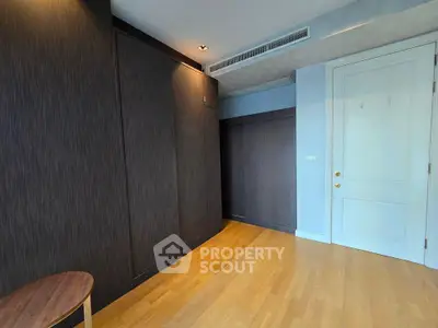 Spacious room with wooden flooring and dark wood paneling, ideal for modern living.