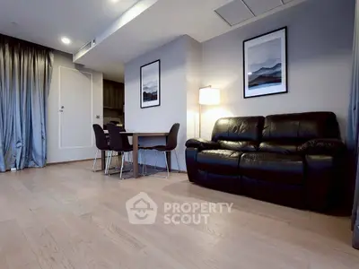 Modern living room with sleek black leather sofa and elegant dining area.