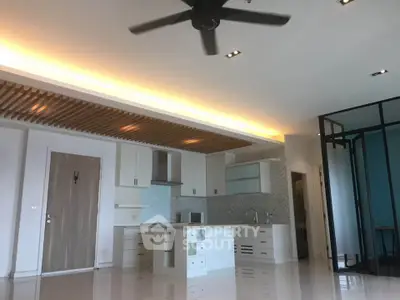 Modern open-layout kitchen with sleek design and ceiling fan in a spacious apartment.
