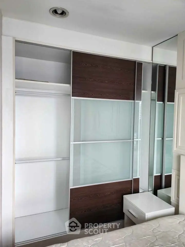 Modern bedroom with sleek built-in wardrobe and mirrored panels, maximizing space and style.