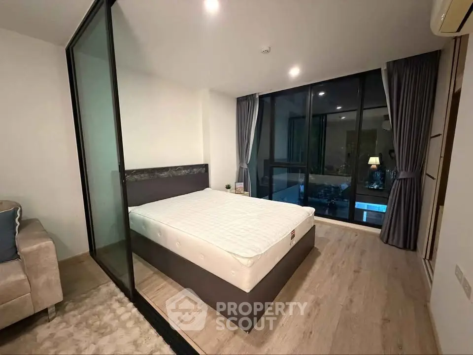 Modern bedroom with glass partition and large window offering natural light