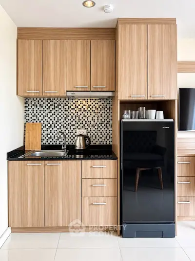 Modern kitchen with wooden cabinets and sleek black fridge in stylish apartment.