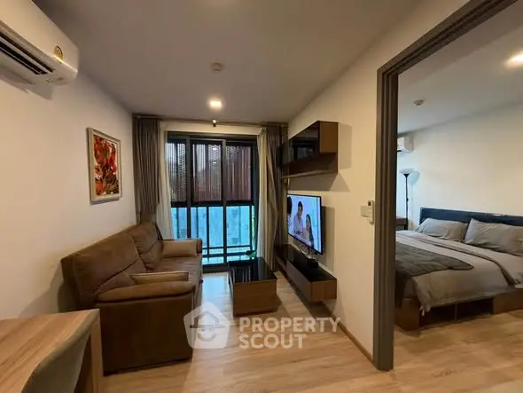 Modern apartment living room with cozy sofa and wall-mounted TV, adjacent to a stylish bedroom.
