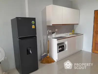 Modern kitchen with sleek cabinetry and black refrigerator in a minimalist design.