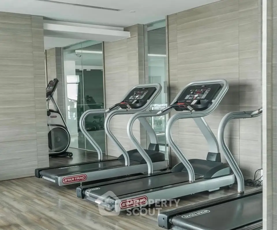 Modern gym with state-of-the-art treadmills and mirrored walls in a luxury residential building.