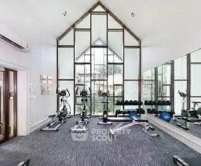 Spacious modern gym with large windows and fitness equipment in a residential building.