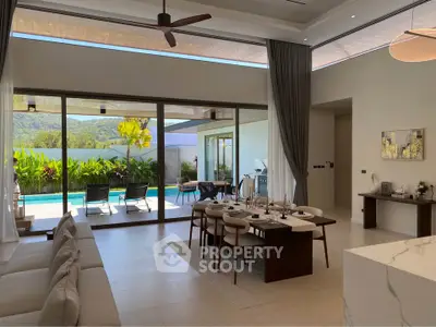 Luxurious open-plan living room with pool view and elegant dining area, perfect for entertaining.