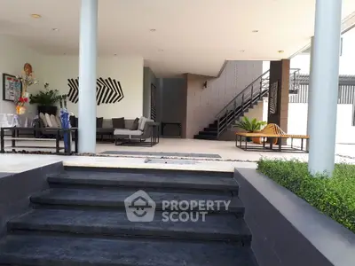 Modern open-concept living area with stylish furniture and staircase, perfect for entertaining.